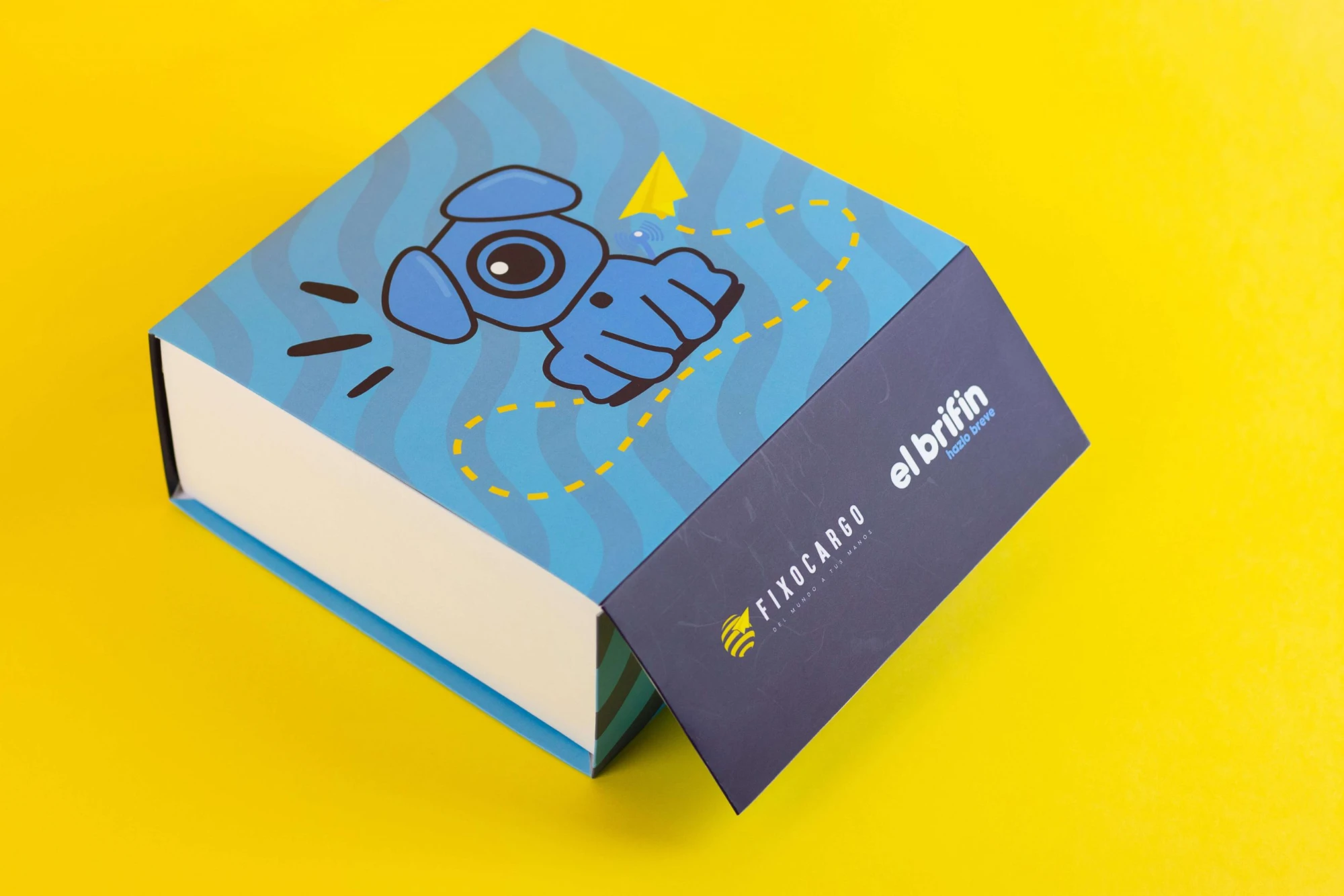 Caja de tapa imantada con la mascota de Fixocargo y los logos de Fixocargo y El Brifin sobre fondo amarillo