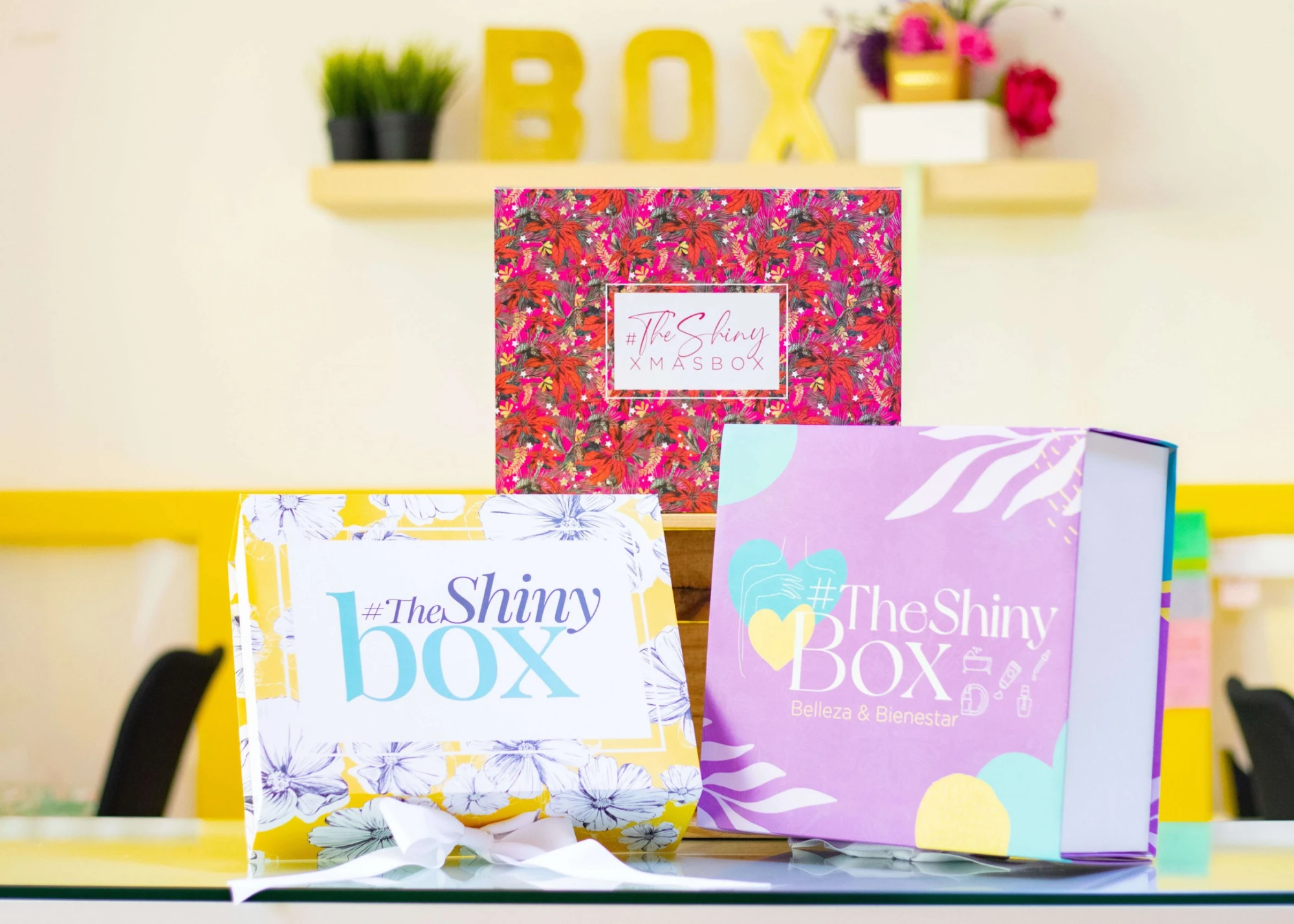 Tres cajas de The Shiny Box: edición floral amarilla, edición navideña y edición lila de belleza y bienestar